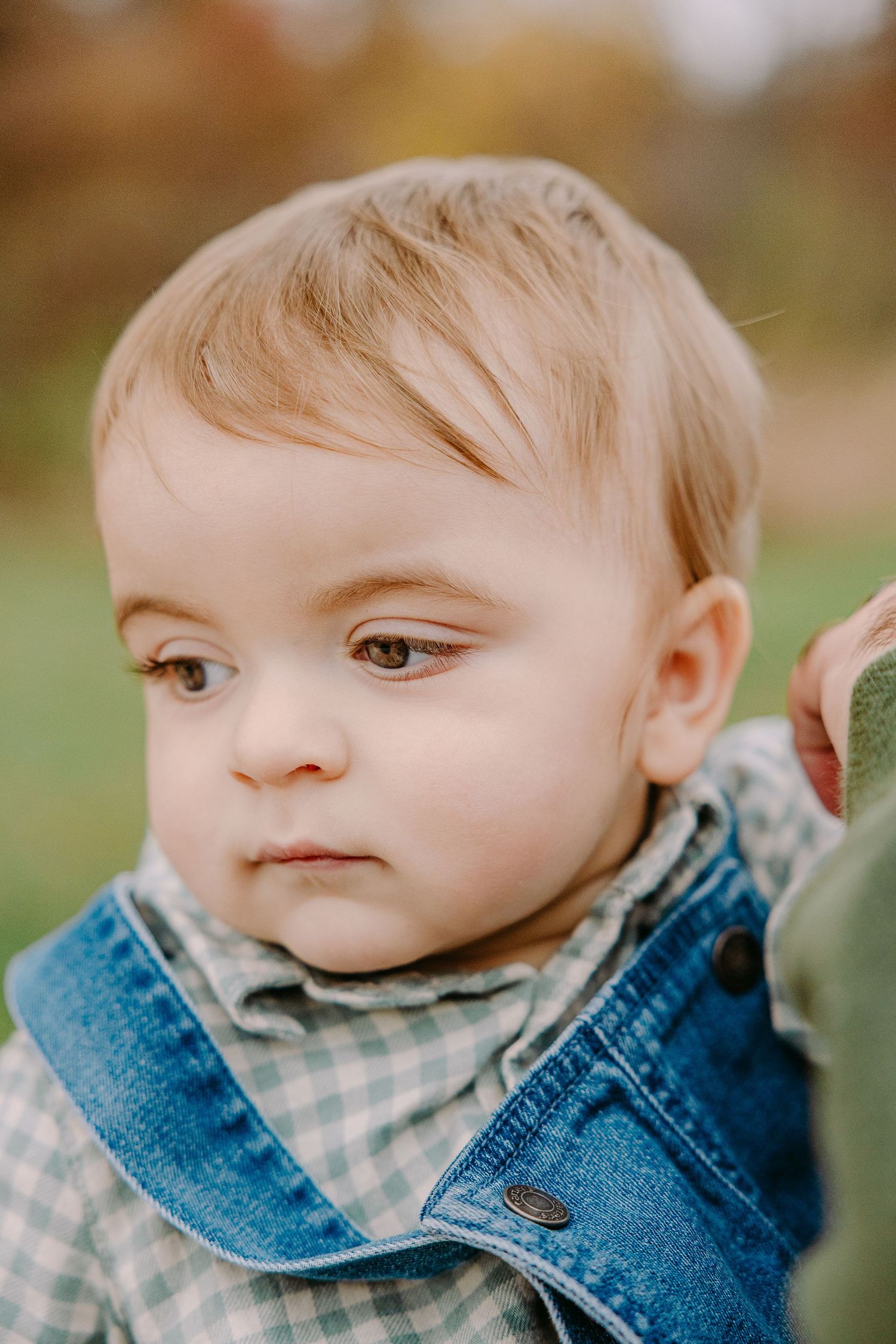 Young child in denim jacket and checkered shirt shown in close-up profile shots. Lifestyle session with warm tones and candid connection in
