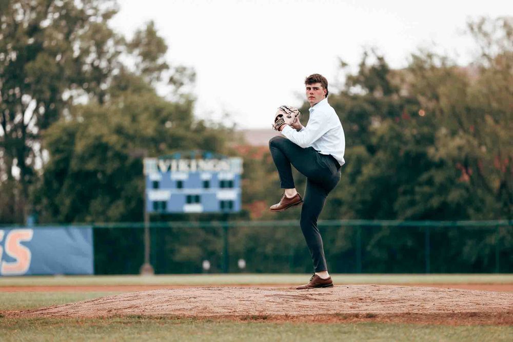 Senior photos in O'Fallon, MO of baseball pitcher follows through on delivery motion during outdoor game on dirt mound at sports field.