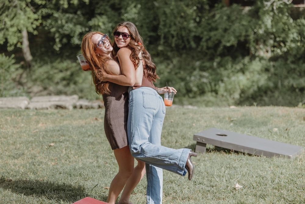 Lifestyle photography session of two people hugging and laughing together in a sunny outdoor setting. Best friend photo session, Harman MO.