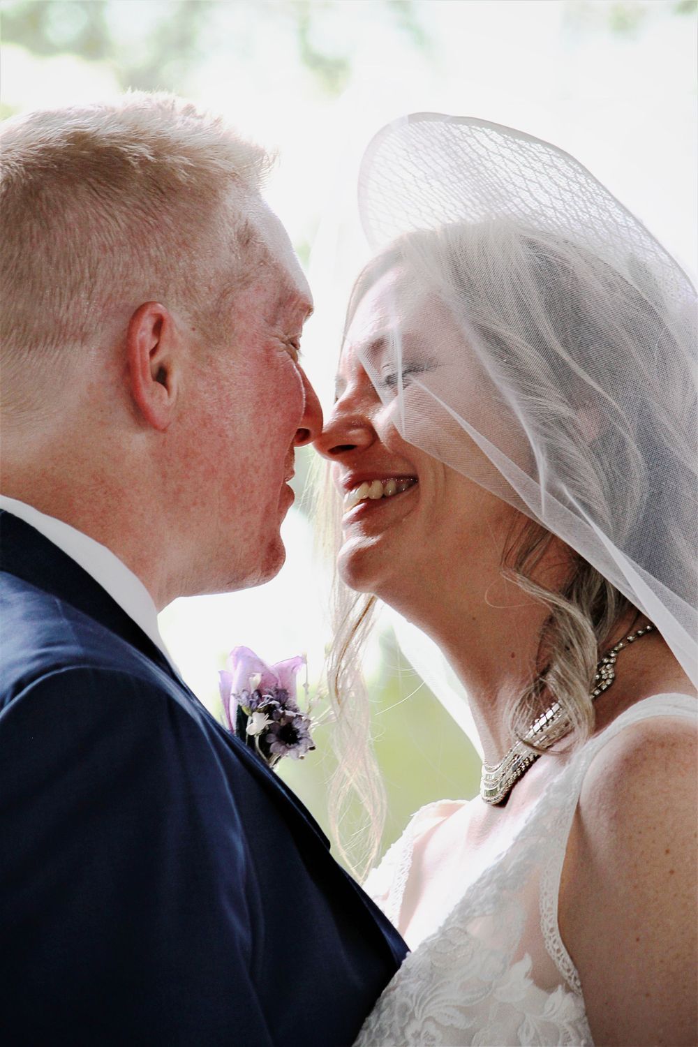 Wedding photography of romantic series of wedding photos showing a couple in a navy suit and white veil sharing tender moments and laughter.