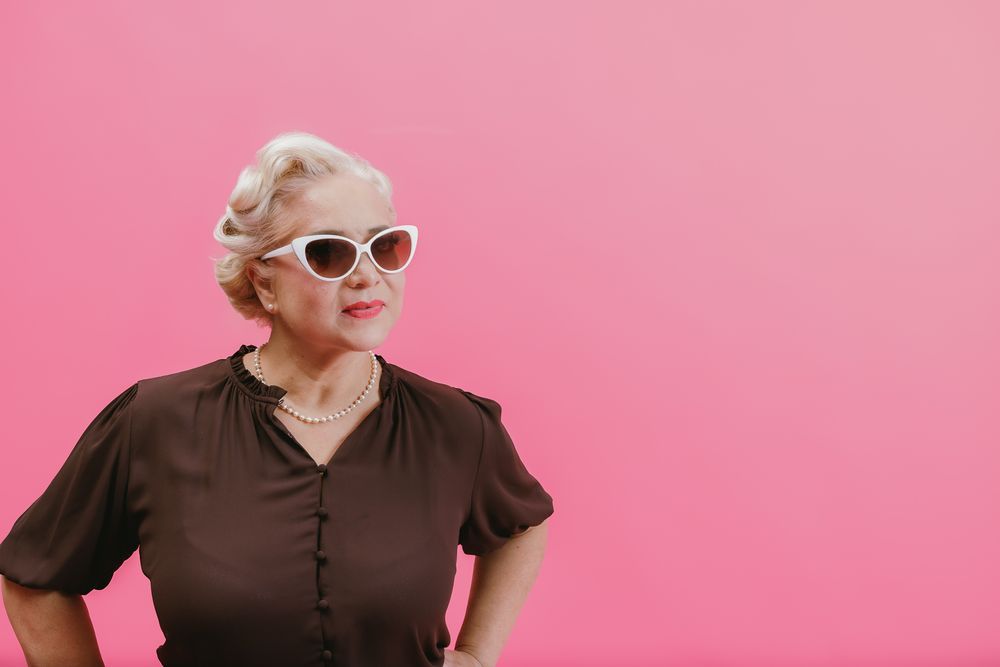 Woman in brown shirt posing against pink background in retro style photoshoot.