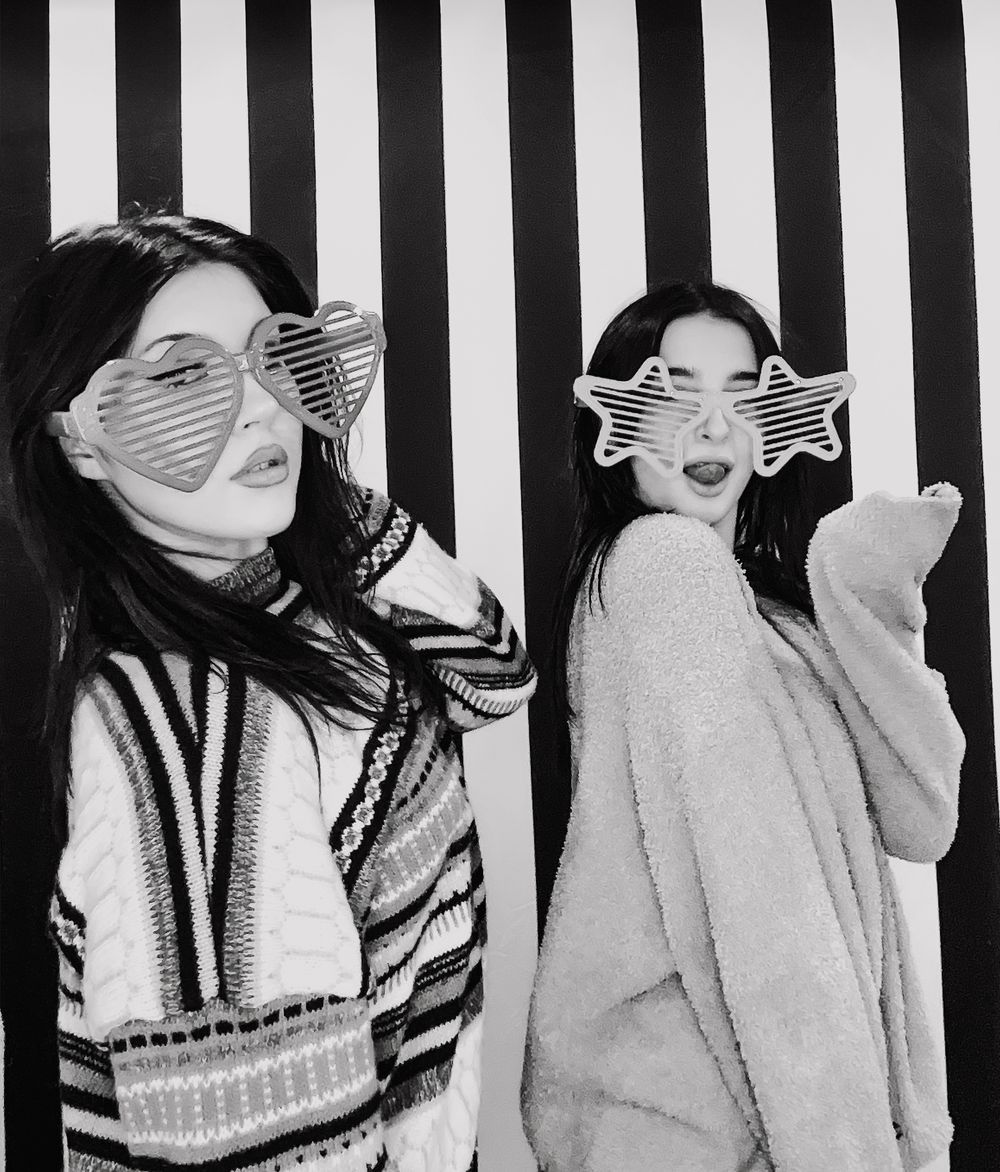 Selfie Photo Booth drop off of Two people wearing star-shaped glasses pose against a black and white striped background in black and white.