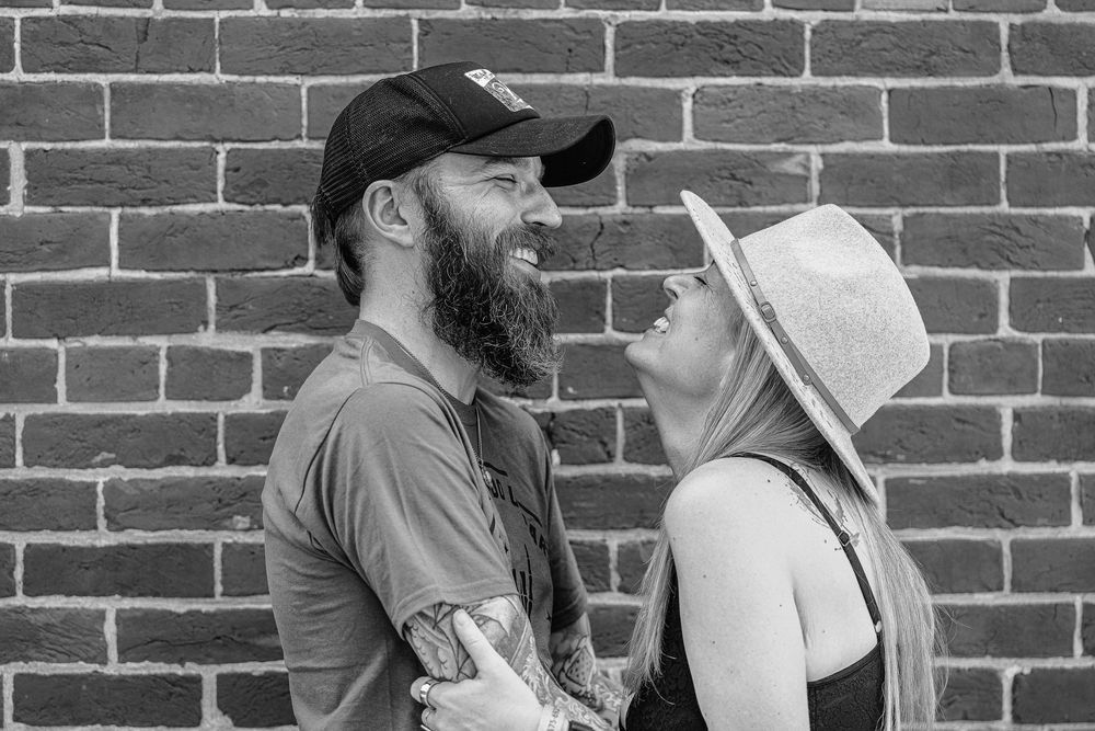 couples in St Charles County. Group of people enjoying drinks and conversation at an outdoor bar against a rustic brick wall backdrop.