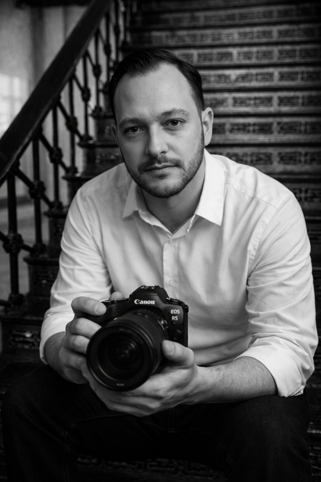 Professional photographer in white shirt holding Canon DSLR camera shown in black and white portrait series.