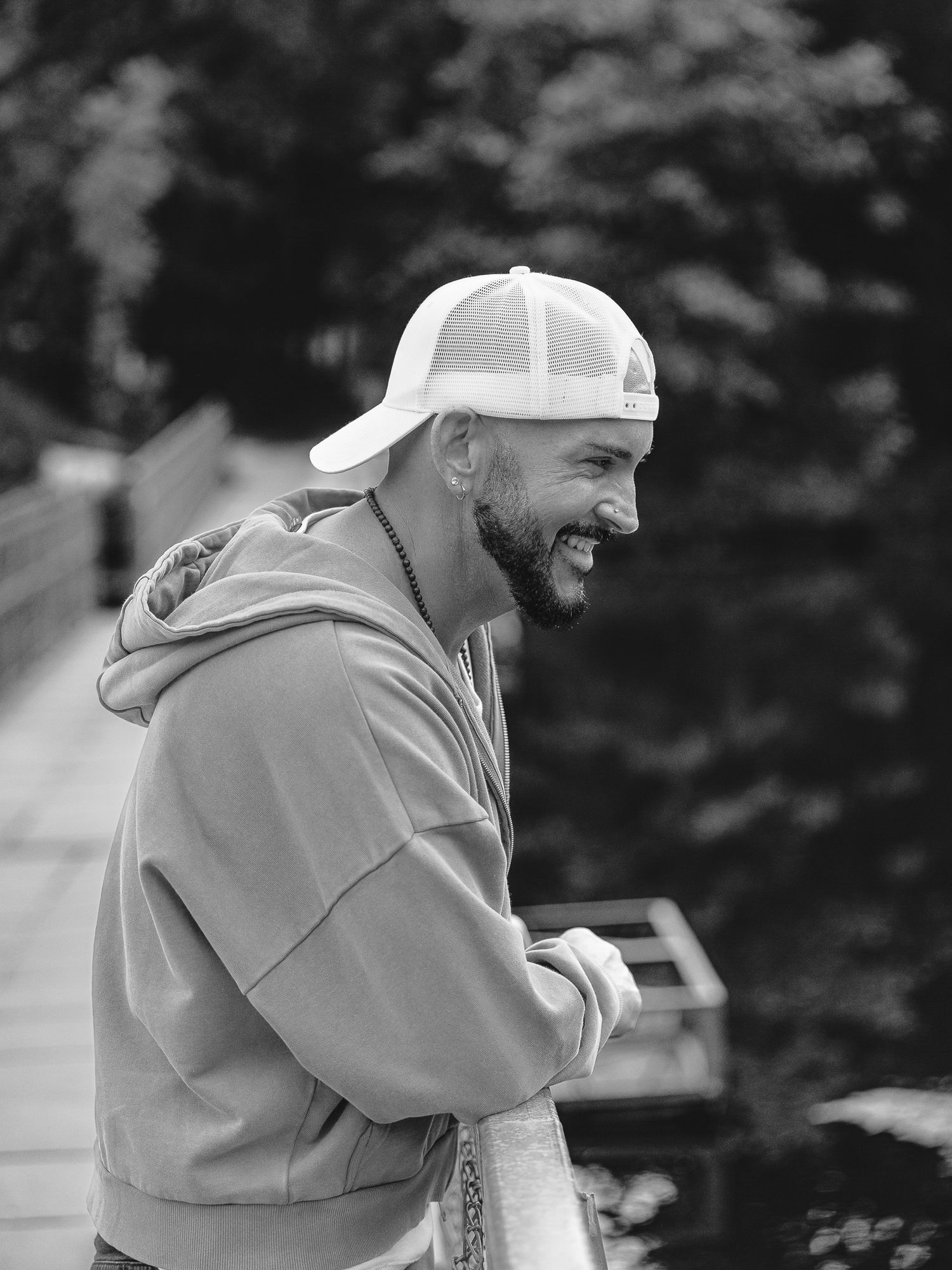 A candid photo session in Klondike Park, Saint Charles of black and white photo of a person in a baseball cap and hoodie laughing outdoors.