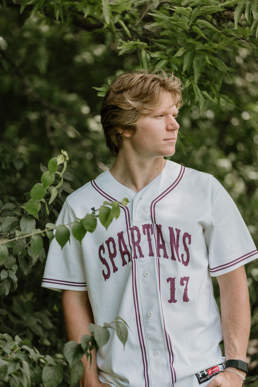 Senior portrait session in O’Fallon, Missouri with authentic expression, confidence, White Spartan jersey, and natural storytelling style.