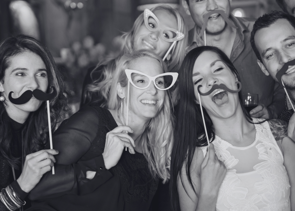 Wedding party using Luxury Photo Booth with fun photo booth props and silly mustaches in black and white in Saint Charles County, Missouri.