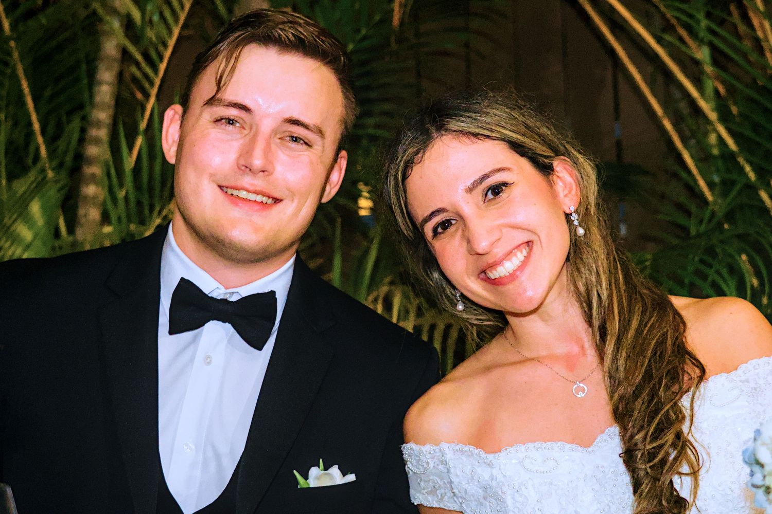 Elegant wedding reception moment captured with tropical foliage in the background.
