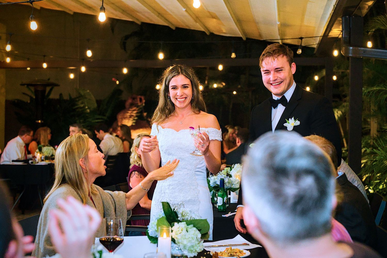 Elegant reception venue decorated with string lights and white ceiling draping for evening celebration.