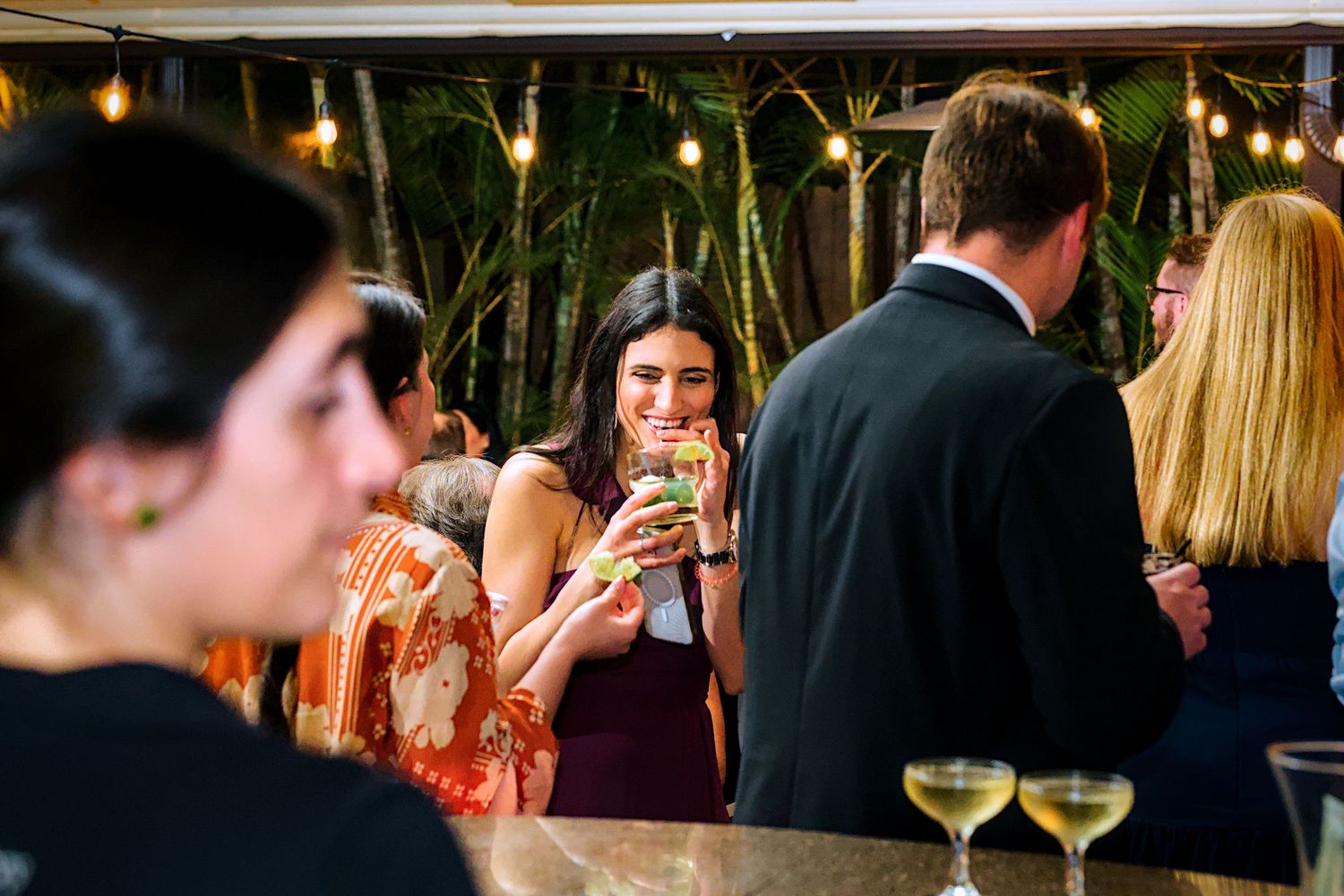 Wedding reception venue with string lights and guests mingling in evening atmosphere.