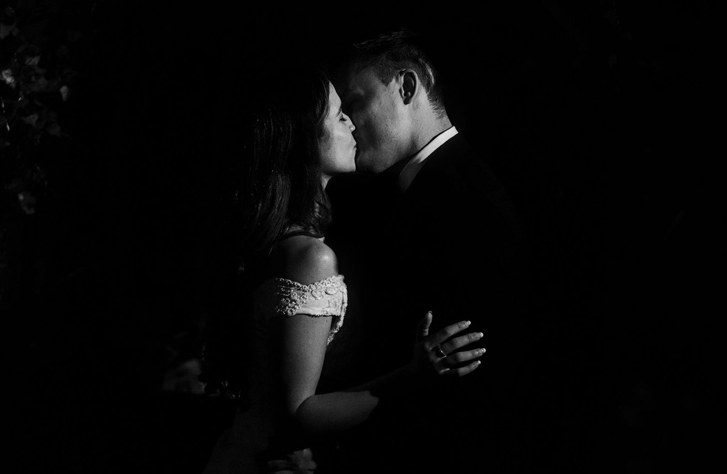 Couples dance intimately on a dimly lit dance floor during an evening wedding celebration.
