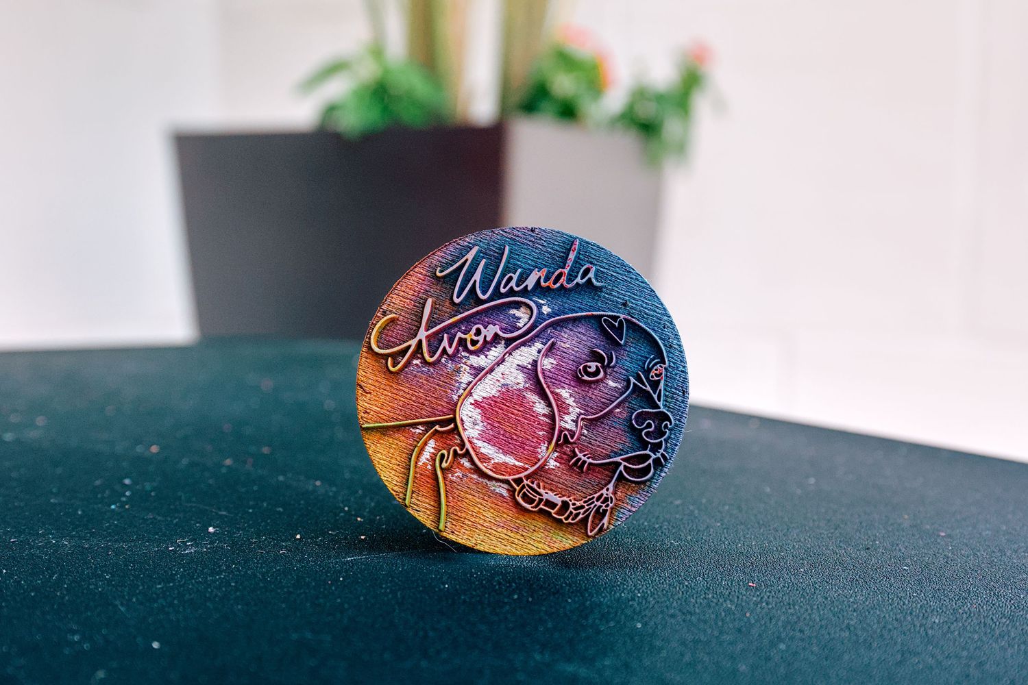 Colorful painted rock featuring a dog portrait with the name Wanda on a teal surface.