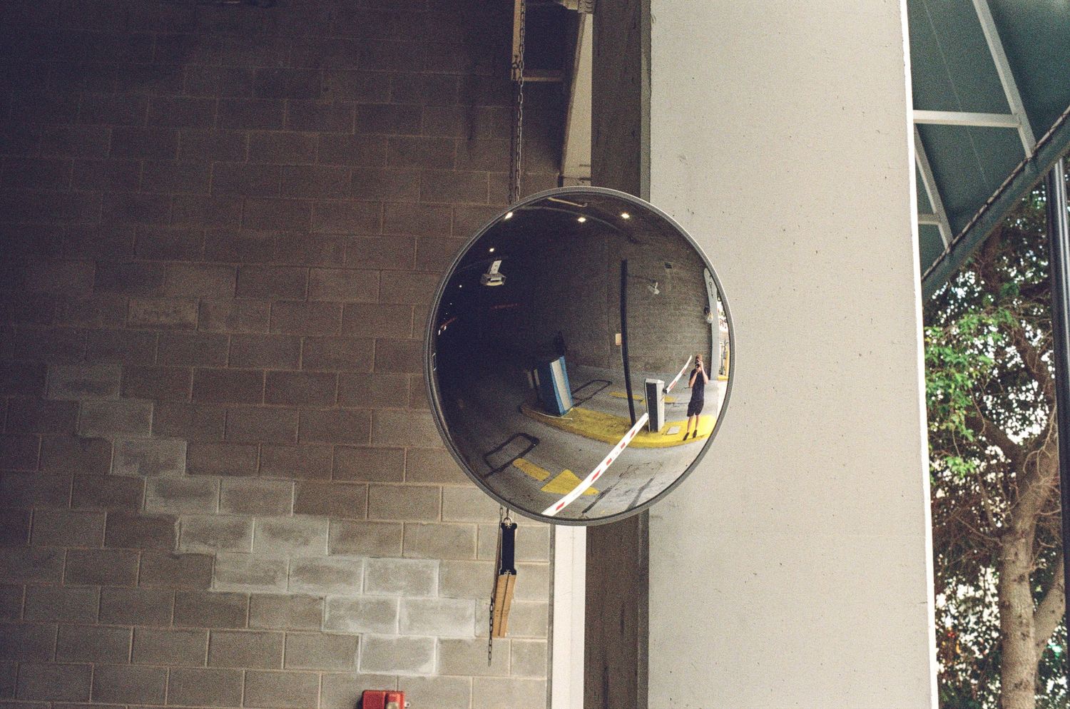 Convex security mirror mounted on a brick wall reflecting a yellow staircase and building interior.