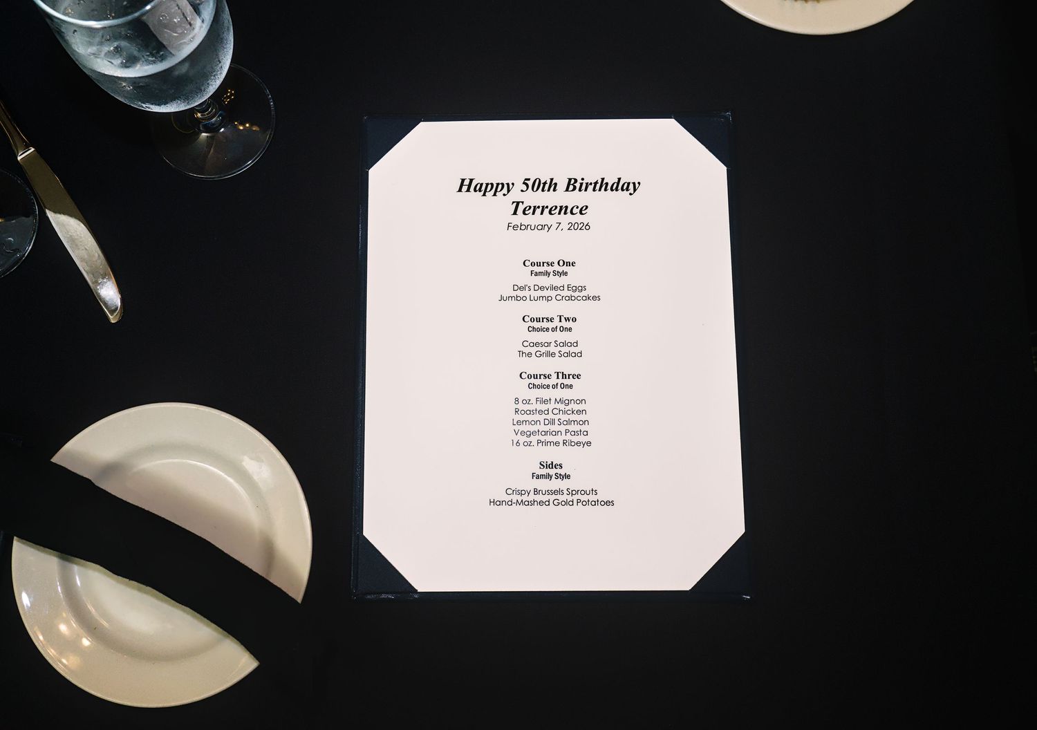 Black and white menu cards and place settings arranged on a formal dining table.