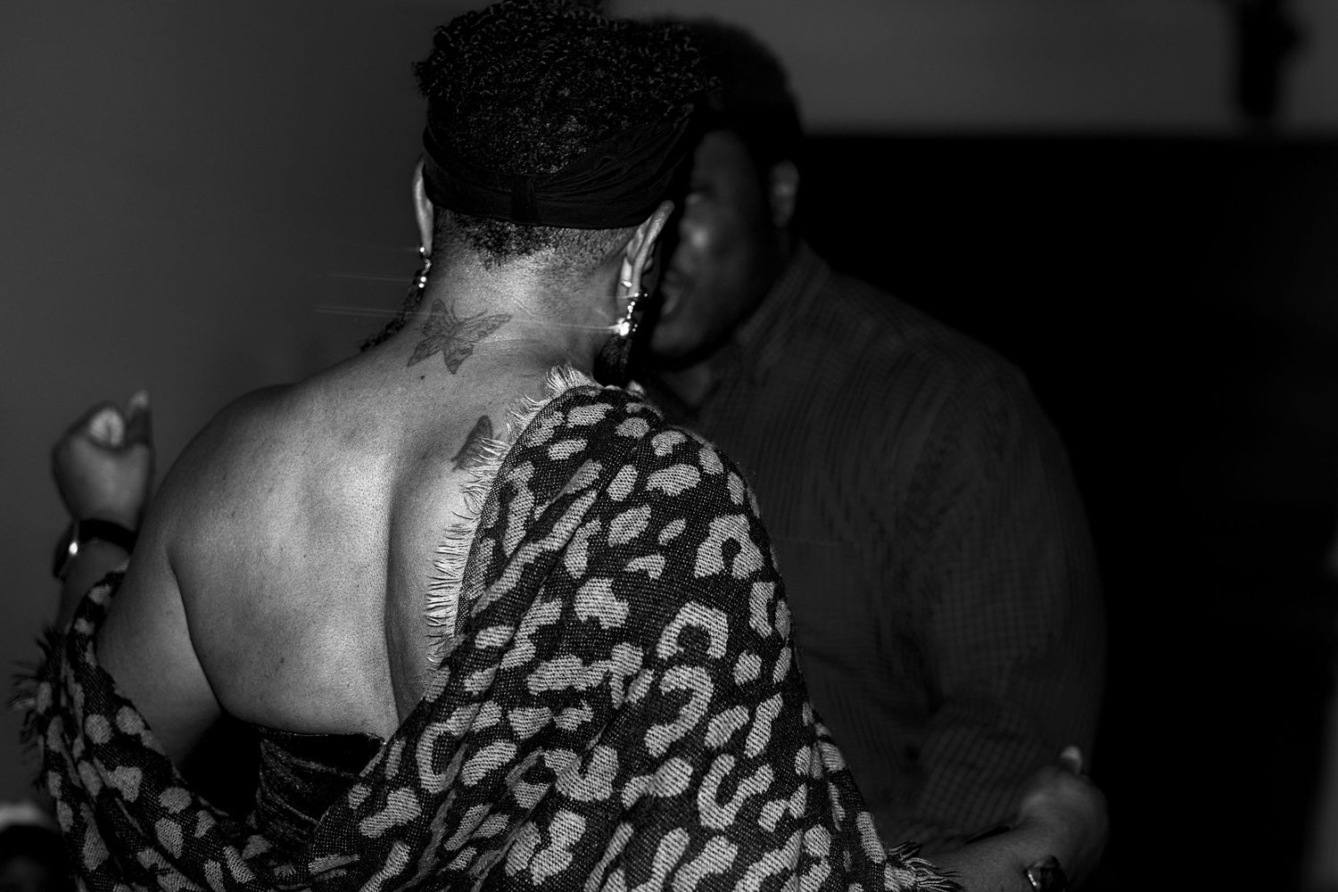 Black and white photo of a woman in leopard print dress dancing with a man at an indoor event.