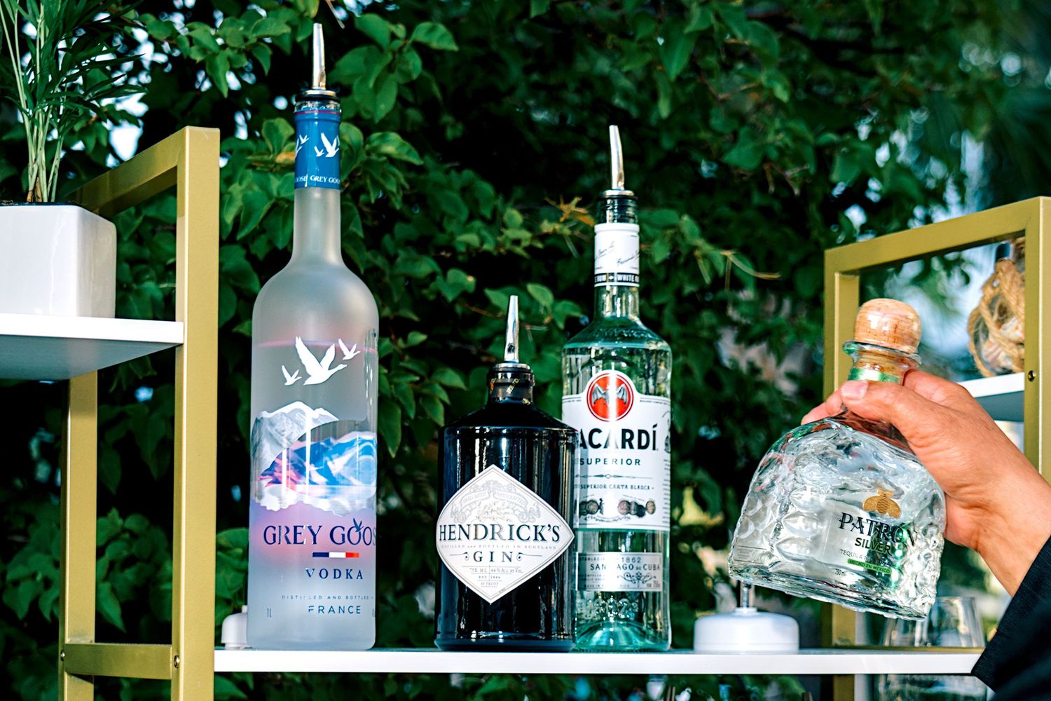 Premium bar cart displaying Grey Goose vodka, Hendricks gin, and Bacardi bottles at outdoor event.