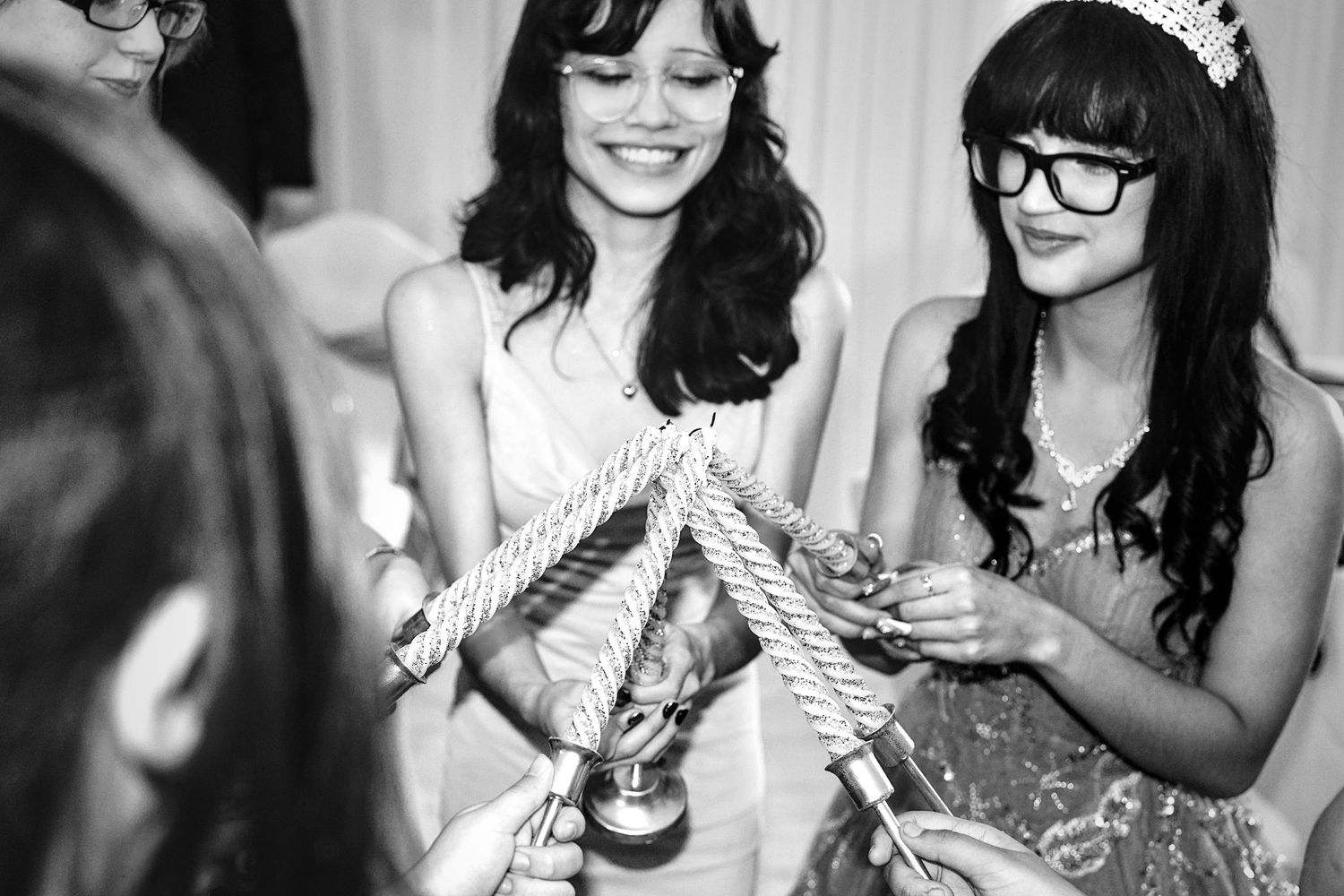 Young women smiling and holding braided rope together at a fun wedding celebration activity.