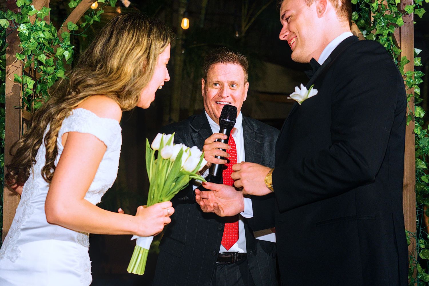 Elegant wedding celebration with guests socializing under twinkling lights and greenery.