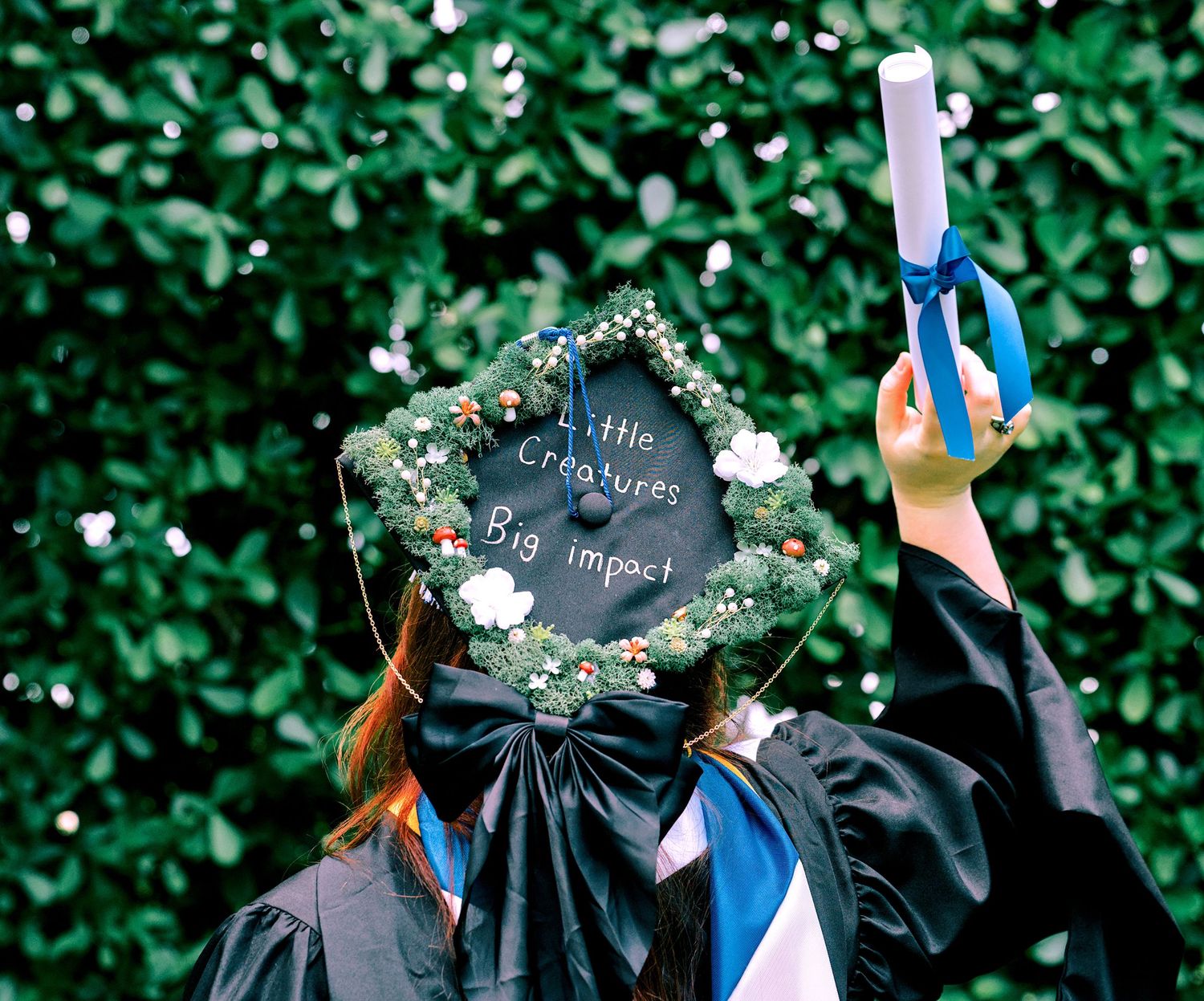 Graduate in black cap decorated with flowers and 