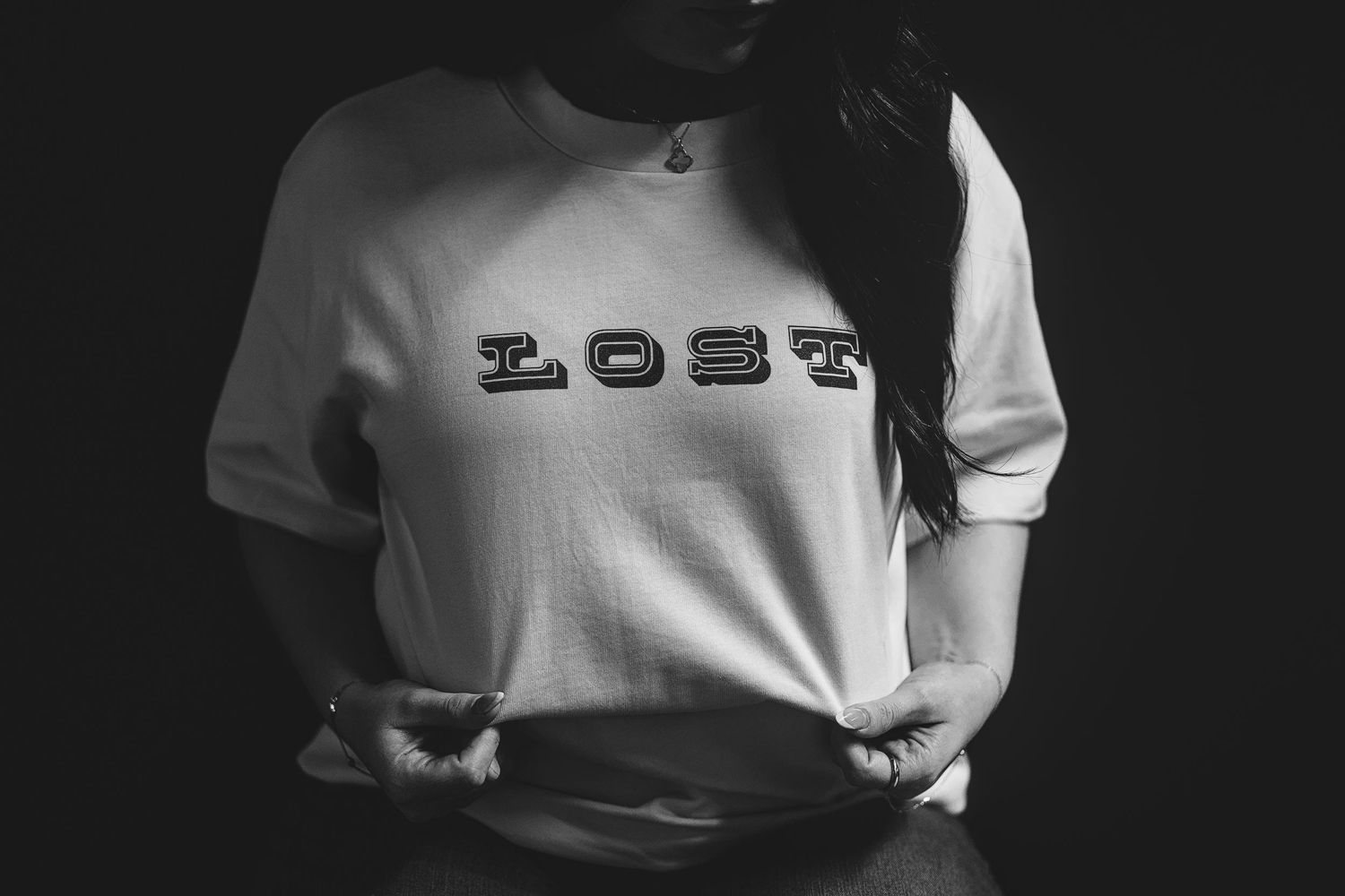 Black and white photo showing text logo on white clothing against dark background.
