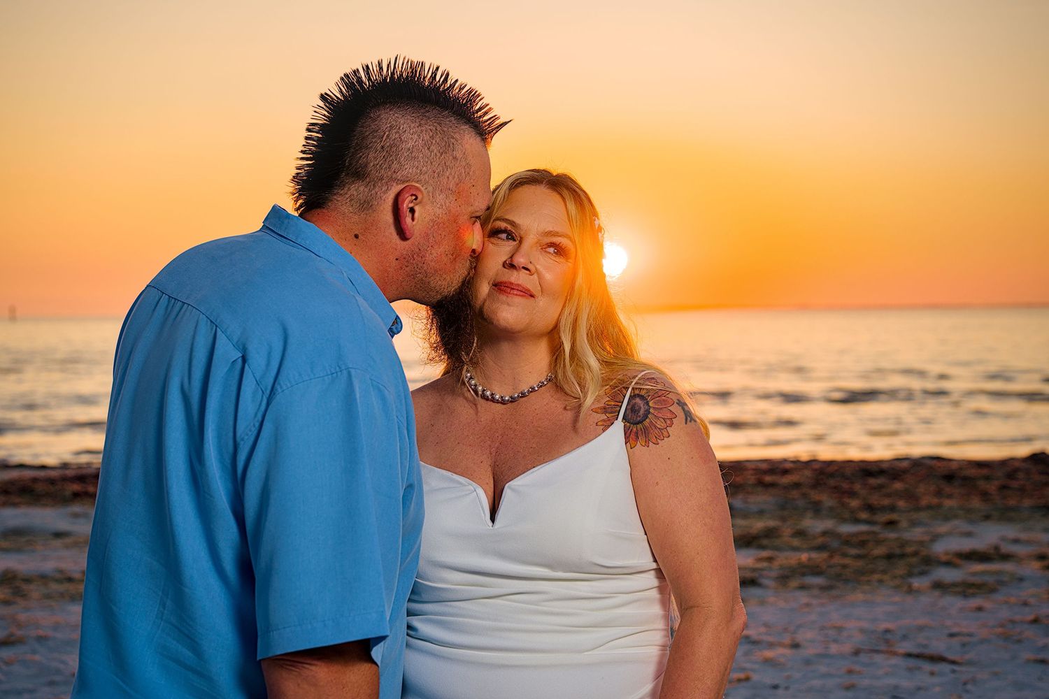 Golden hour beach portraits showing intimate moments between a couple against an orange sunset sky.