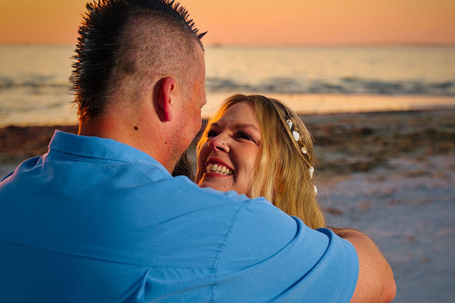 A romantic sunset beach wedding portrait with orange sky in the background.