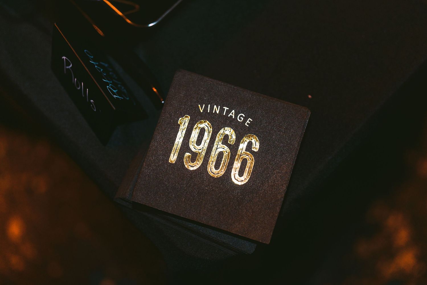 Vintage 1966 gold embossed text on a dark decorative box displayed on a table.