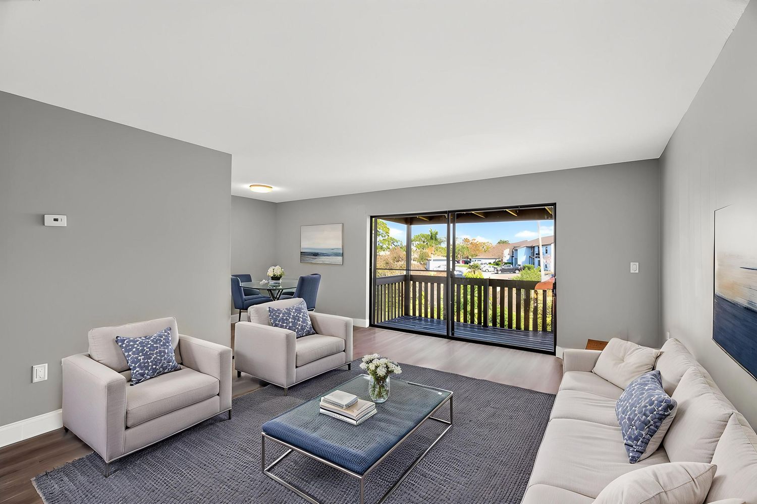 Modern living room with gray walls, beige furniture, and a balcony offering scenic mountain views through large windows.