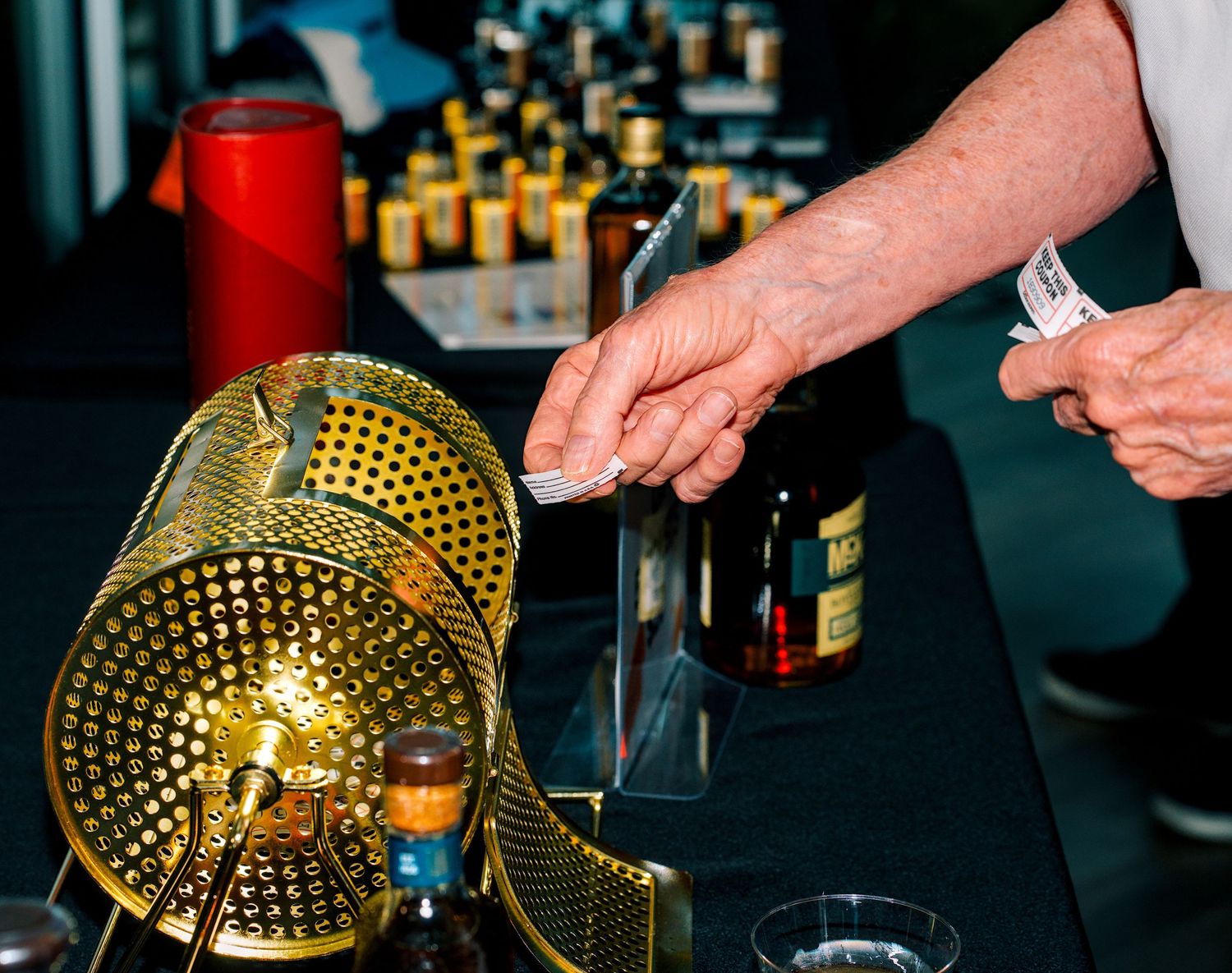 A bartender pours spirits from a bottle at an elegant bar setup with golden decor and various liquor bottles.