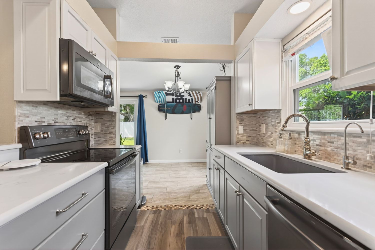 Modern kitchen with white cabinets, stainless steel appliances, subway tile backsplash, quartz countertops, and hardwood floors.