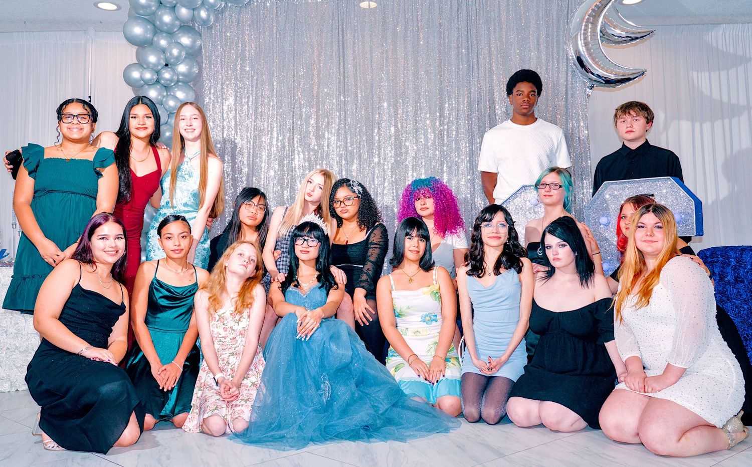 Group of teens posing together at a prom or formal dance event with balloon decorations.