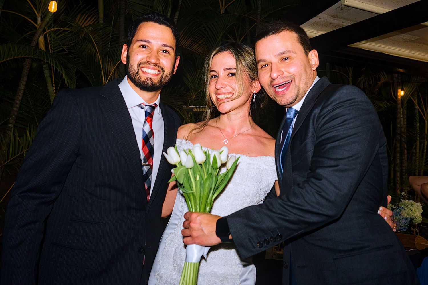 Wedding party members share joyful moments during an outdoor evening celebration.