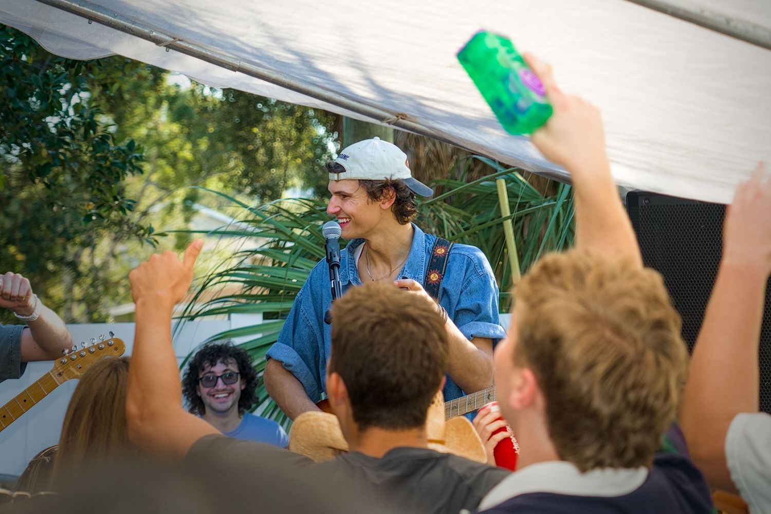 Crowd of excited people with raised arms at an outdoor event.