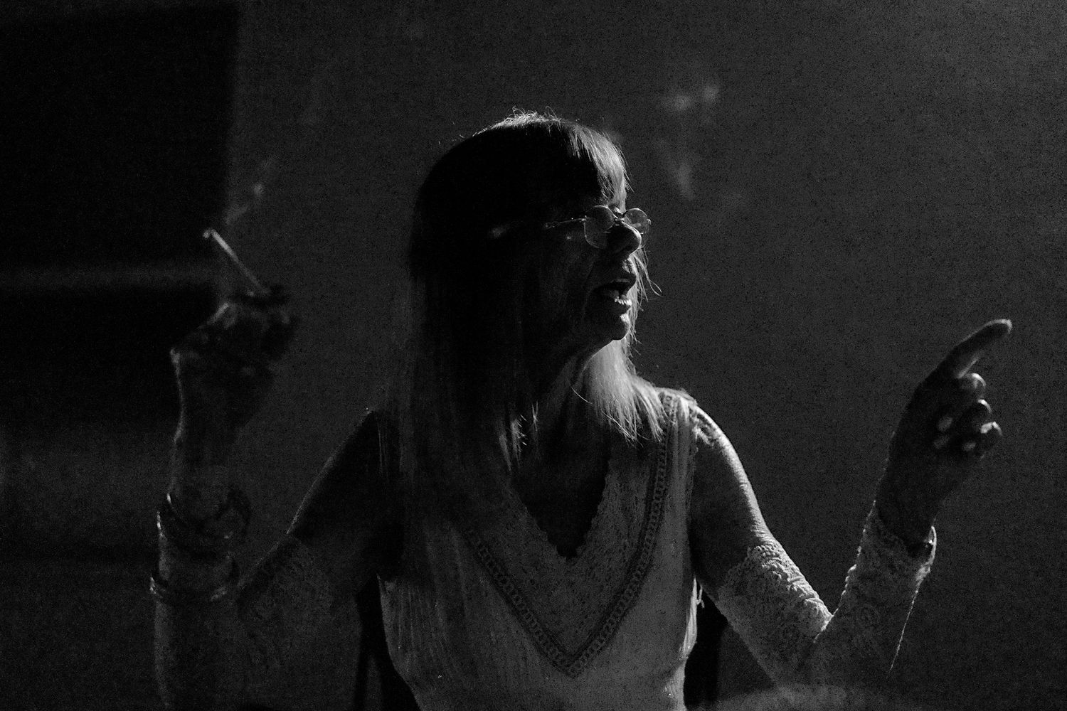 Black and white photo of a woman dancing expressively at a wedding reception.