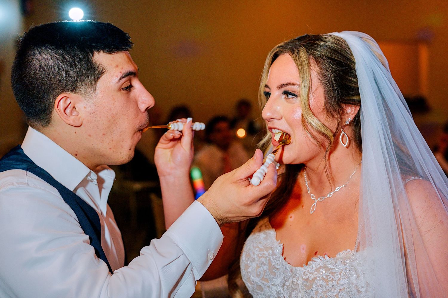 Bride and groom feed each other wedding cake during their romantic reception celebration.