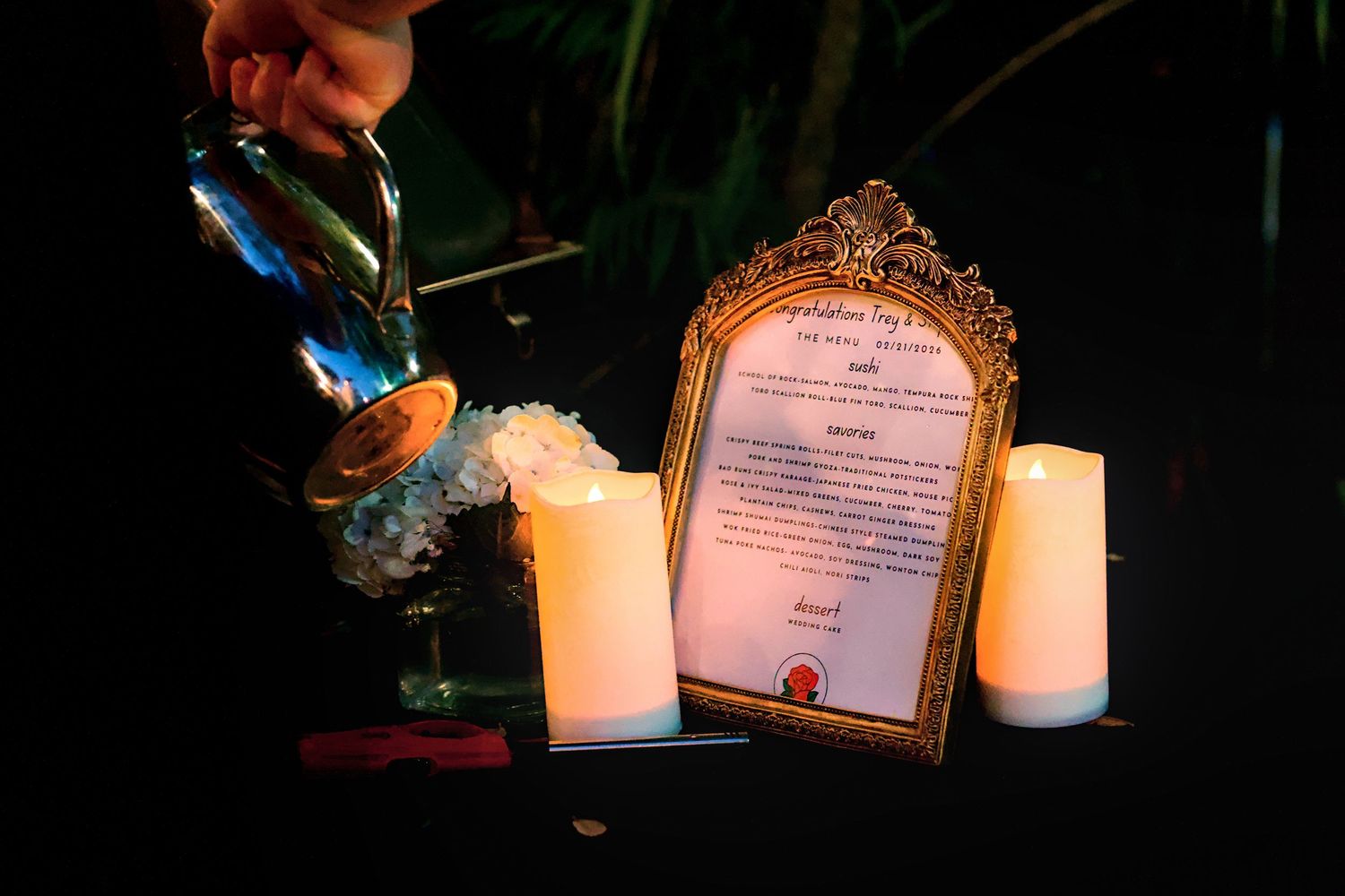 A row of lit white candles illuminates certificates and decorative items on a dark surface in an intimate setting.