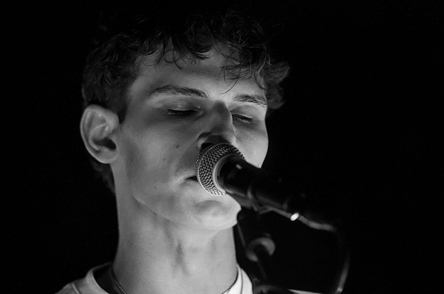 A black and white close-up of a singer performing with a microphone.
