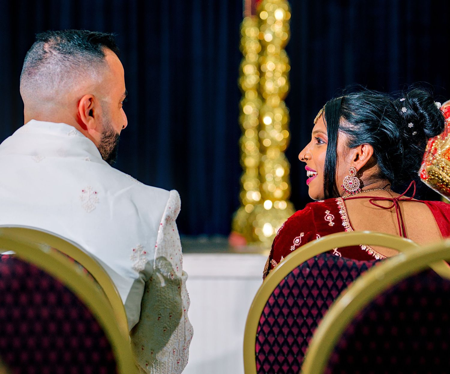 Bride and groom sharing a joyful moment during a traditional South Asian wedding ceremony.