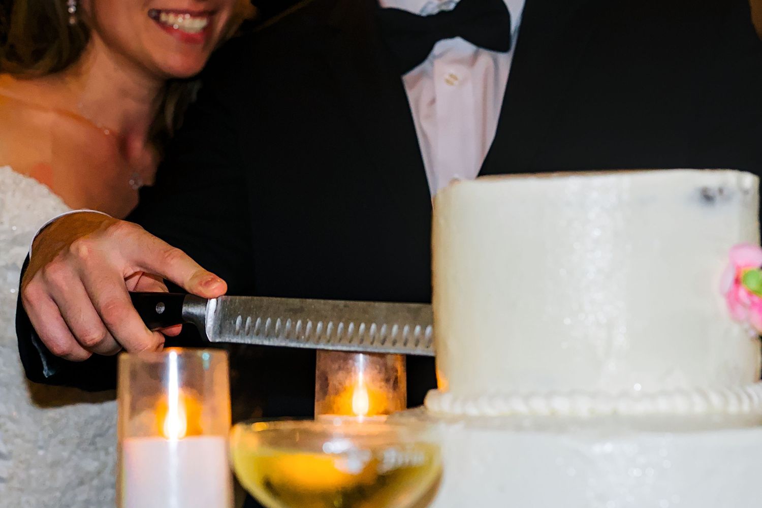 Wedding reception details with candlelight and cake in soft focus.