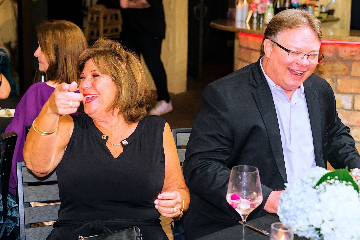 Wedding reception guests enjoying dinner and conversation at decorated tables.