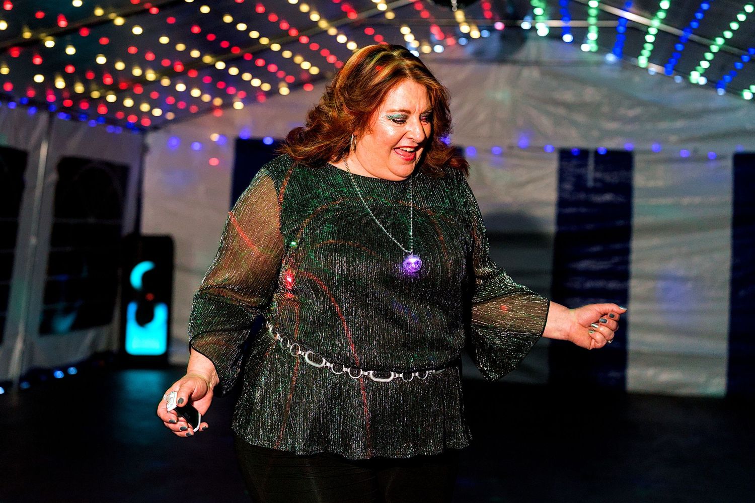 Woman in green top dancing under colorful lights at a festive party event.