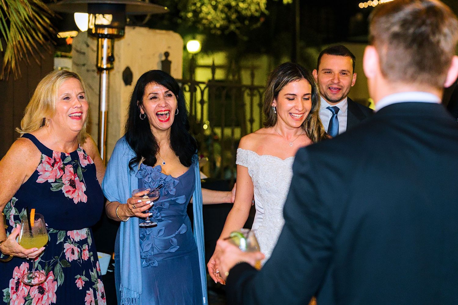Wedding guests laughing and enjoying themselves at an outdoor evening reception.