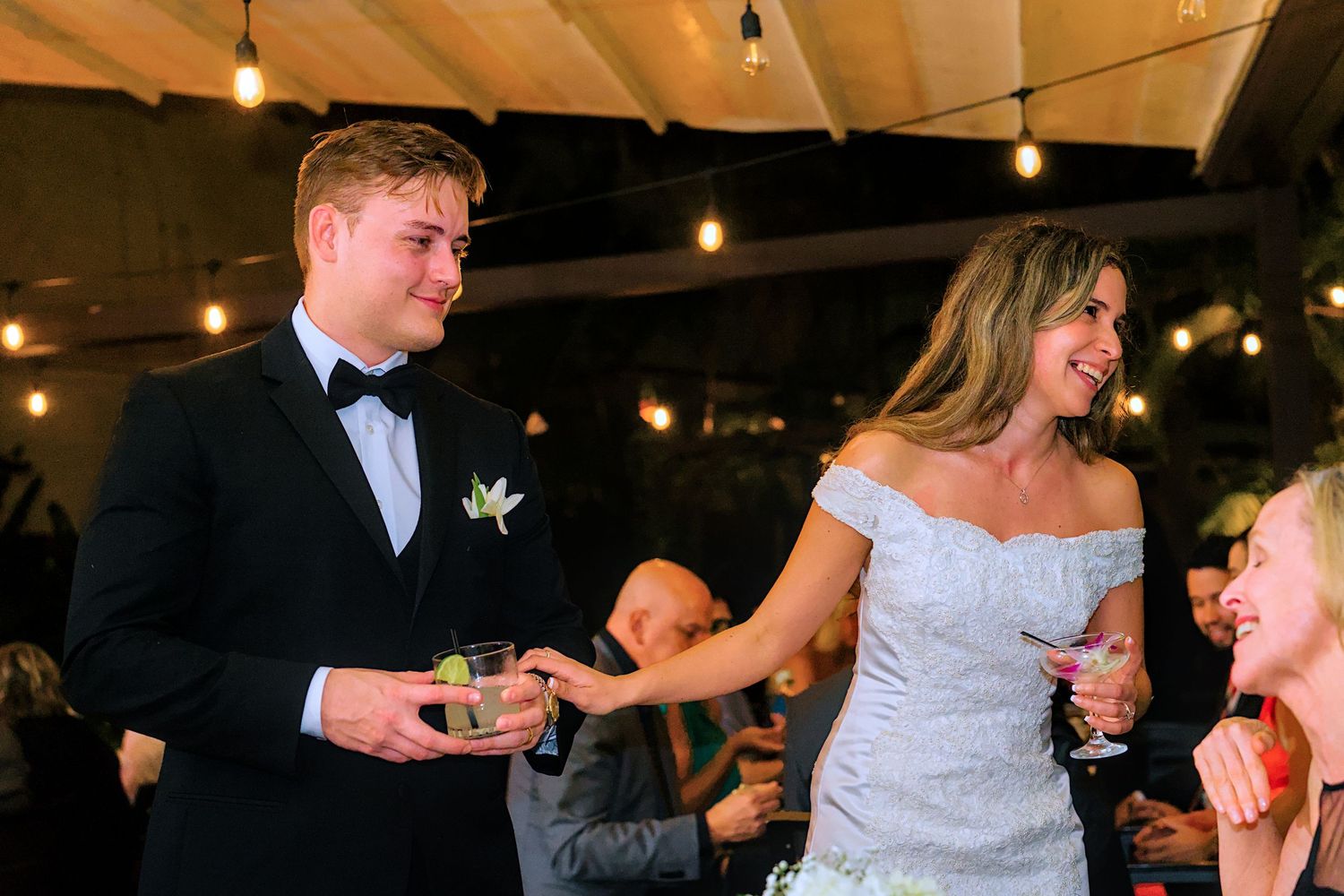 Wedding reception dance floor with string lights overhead and wooden beams.