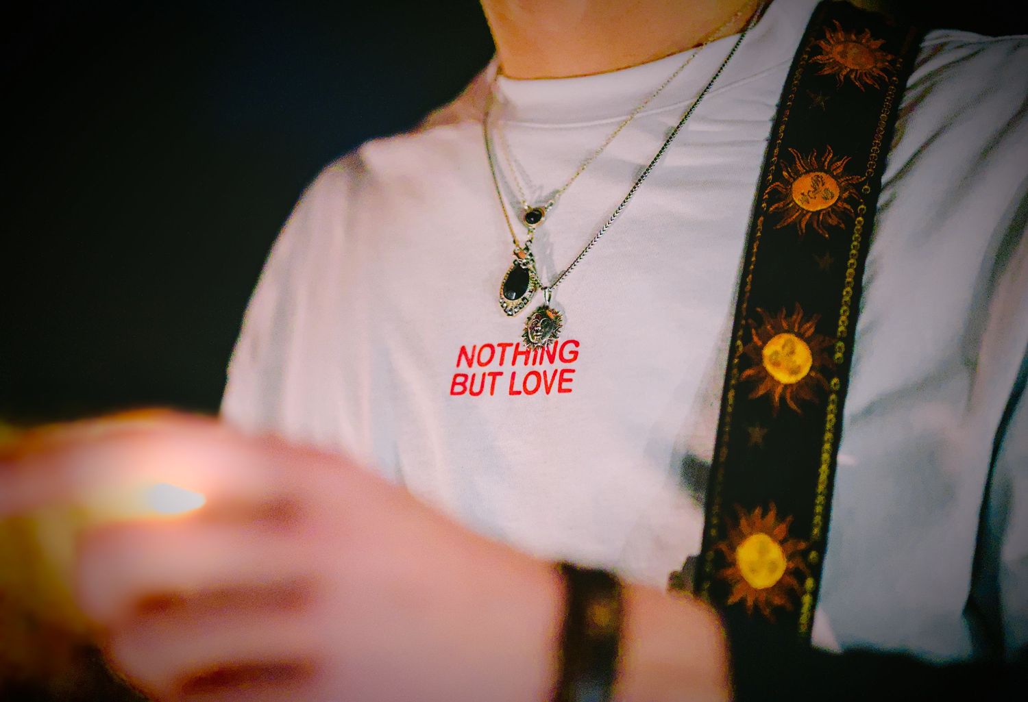 A white t-shirt with 'Nothing But Love' text and a decorative guitar strap visible.