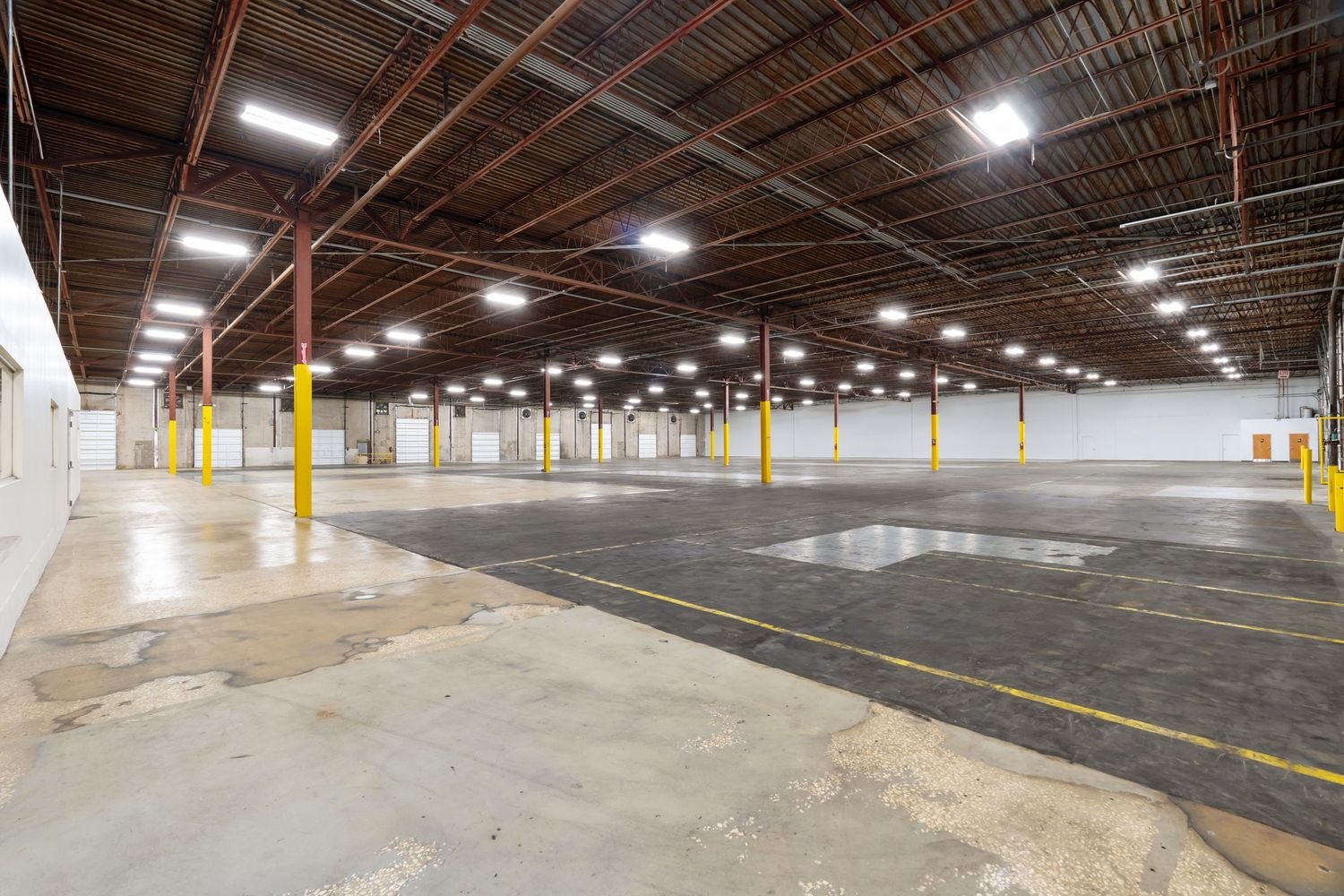 Large empty underground parking garage with concrete pillars and bright overhead lighting.