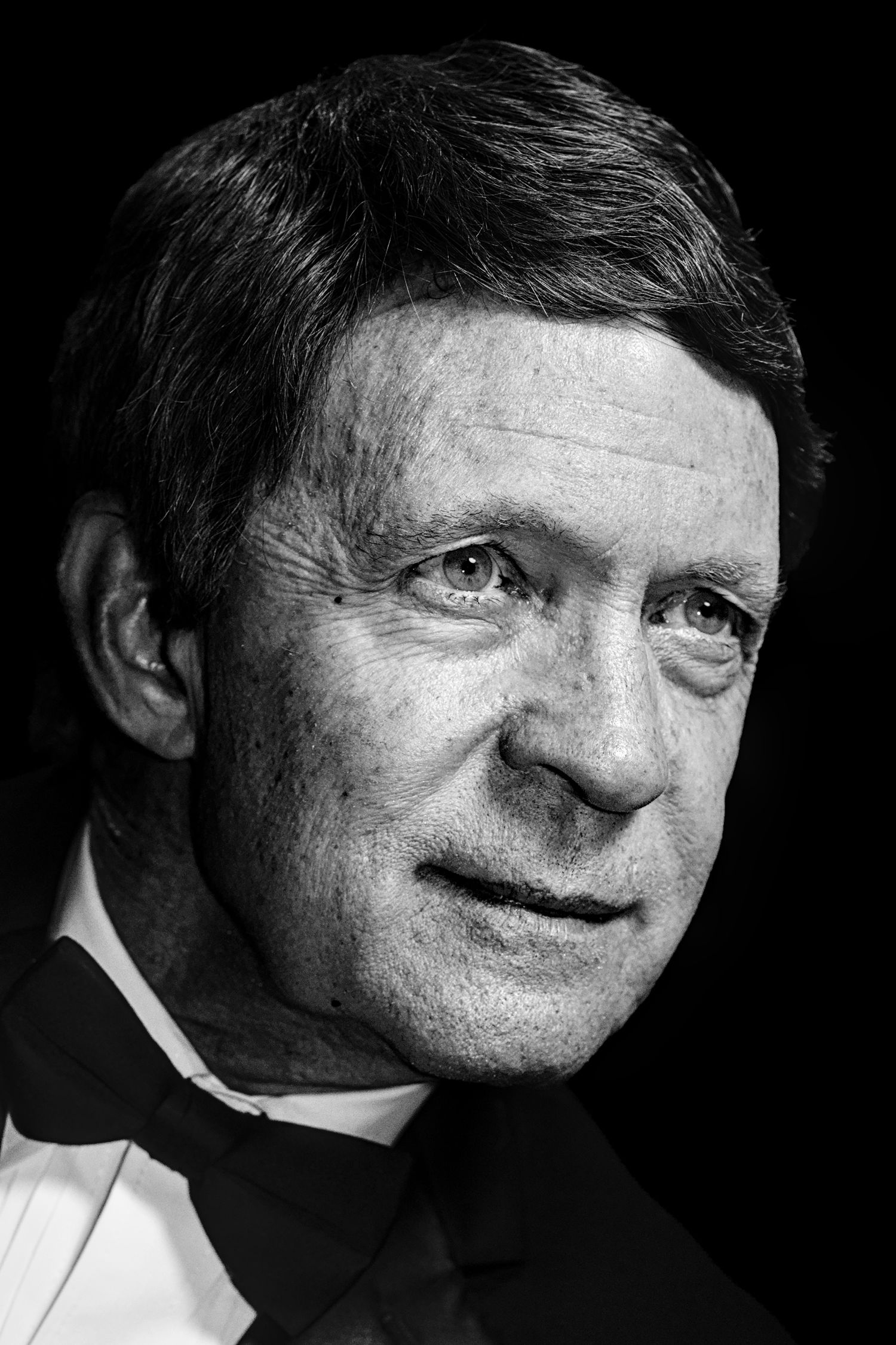 Black and white portrait of a middle-aged man in a tuxedo with bow tie, looking thoughtfully at the camera.