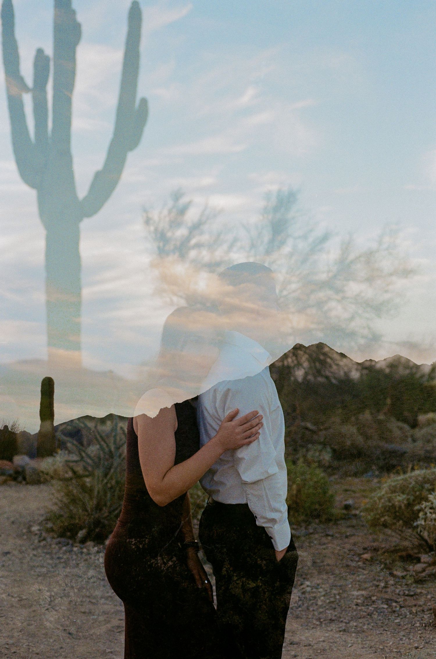 Double exposure photo of a couple kissing in the Sonoran Desert with saguaro cacti and mountains.