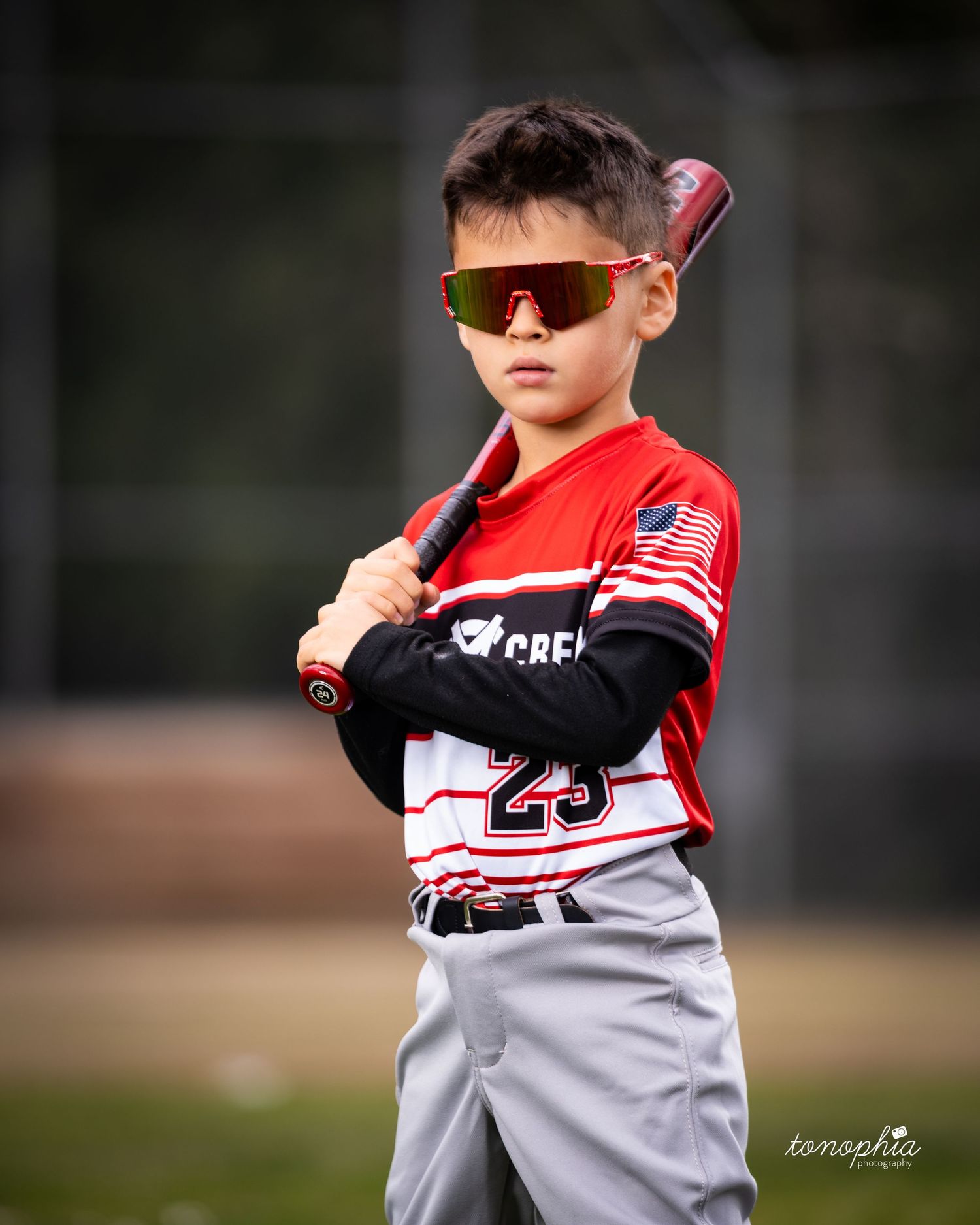 Baseball player in red and white uniform holds bat in ready position during batting practice.