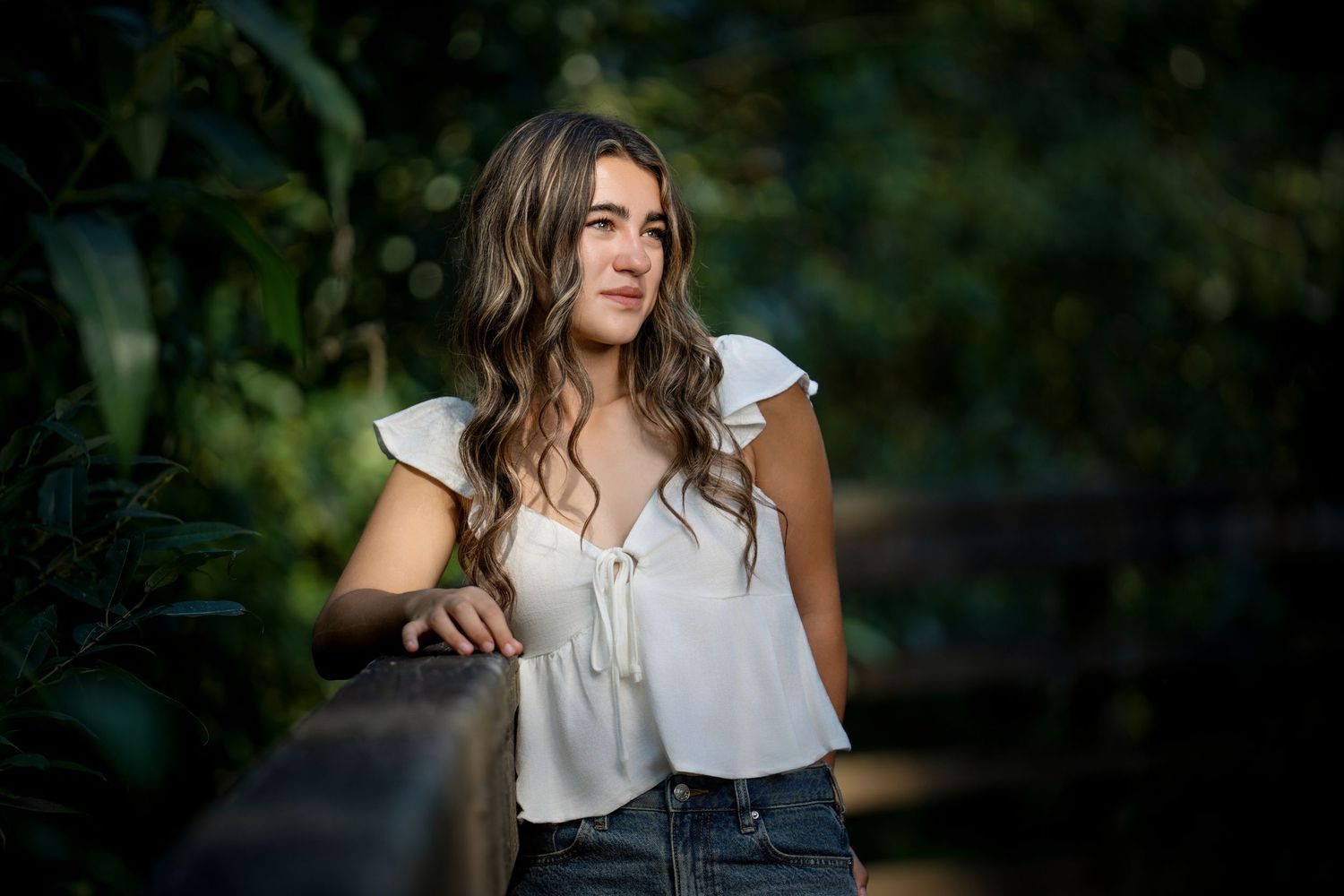Summer portrait in white top against blurred green foliage.