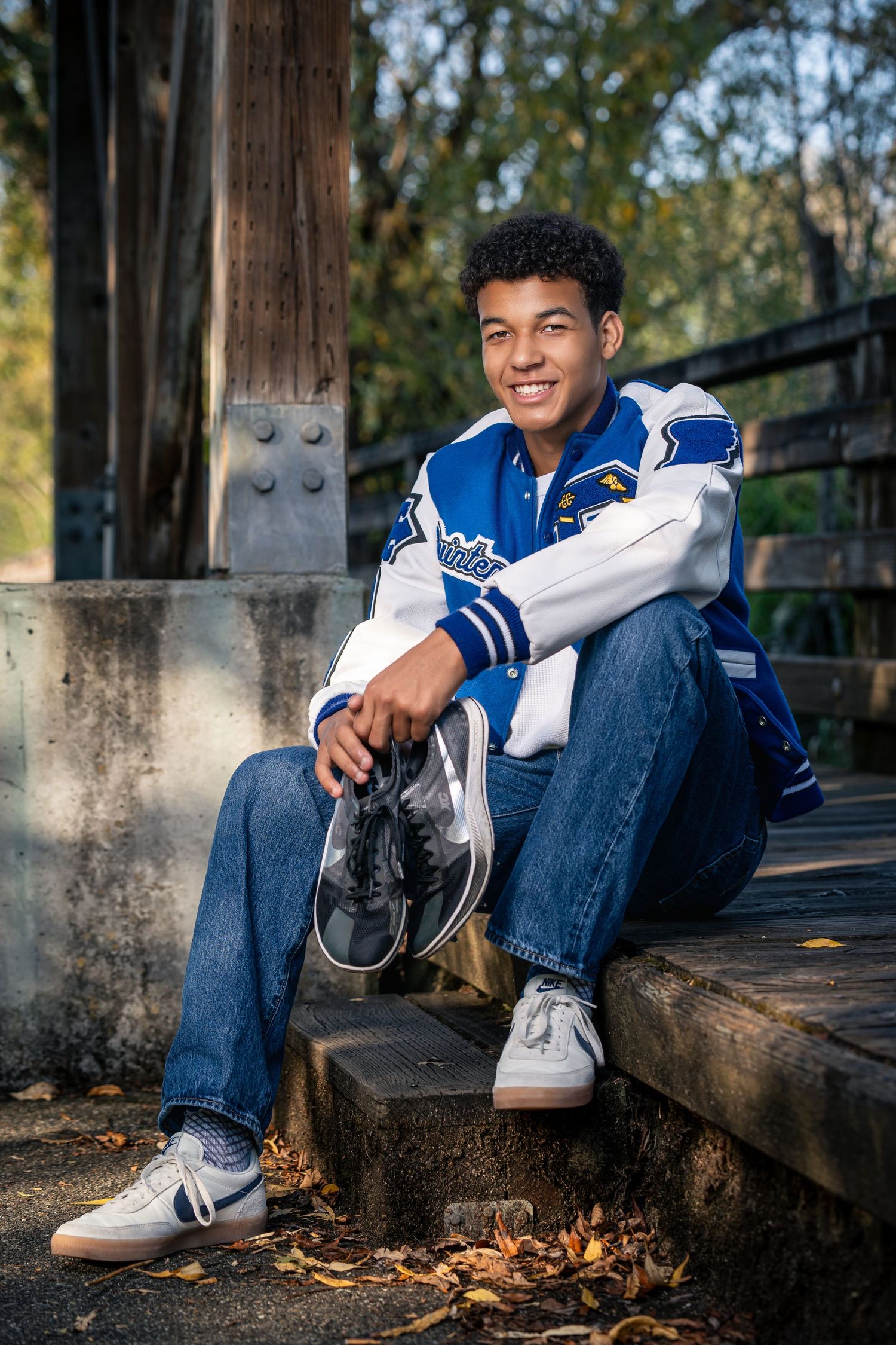 Athletic shoes and casual wear shown against wooden steps with autumn leaves scattered about.